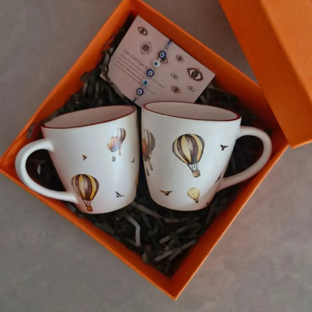Premium Rakhi Gift Hamper with Evil Eye Rakhi & Lumba, Set of 2 Whimsical Hot Air Balloon Ceramic Coffee Mugs & Greeting Card | Luxury Raksha Bandhan Gift Box for Bhai & Bhabhi The confetti tree