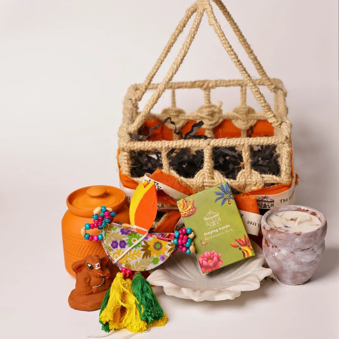 Eco-Friendly Soil Inspired Gift Hamper with Jute Basket, Terracotta Jar of Cashews, Marble Urli, Toran, Playing Cards, Terracotta Candle & Plantable Ganesh The confetti tree