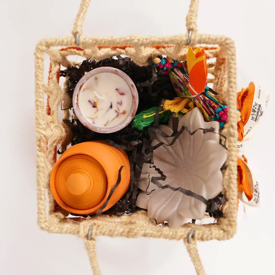 Eco-Friendly Soil Inspired Gift Hamper with Jute Basket, Terracotta Jar of Cashews, Marble Urli, Toran, Playing Cards, Terracotta Candle & Plantable Ganesh The confetti tree