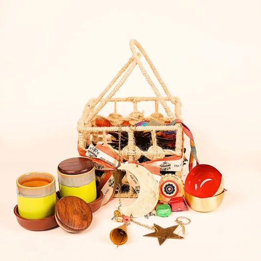 Festive Joy Gift Hamper with Jute Basket, Brass Diyas, Ceramic Tumblers with Dry Fruits, Metal Windchime & Seed Crackers The confetti tree