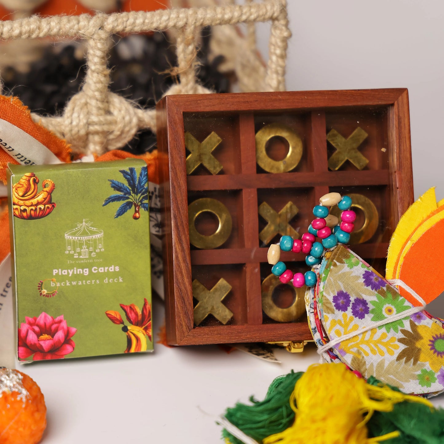 Luxury Jute Gift Basket with Wooden Tic Tac Toe, Brass Diyas, Toran, Laddoo Candles, Mukhwas Jar & Playing Cards – Festive Gifting Hamper The confetti tree