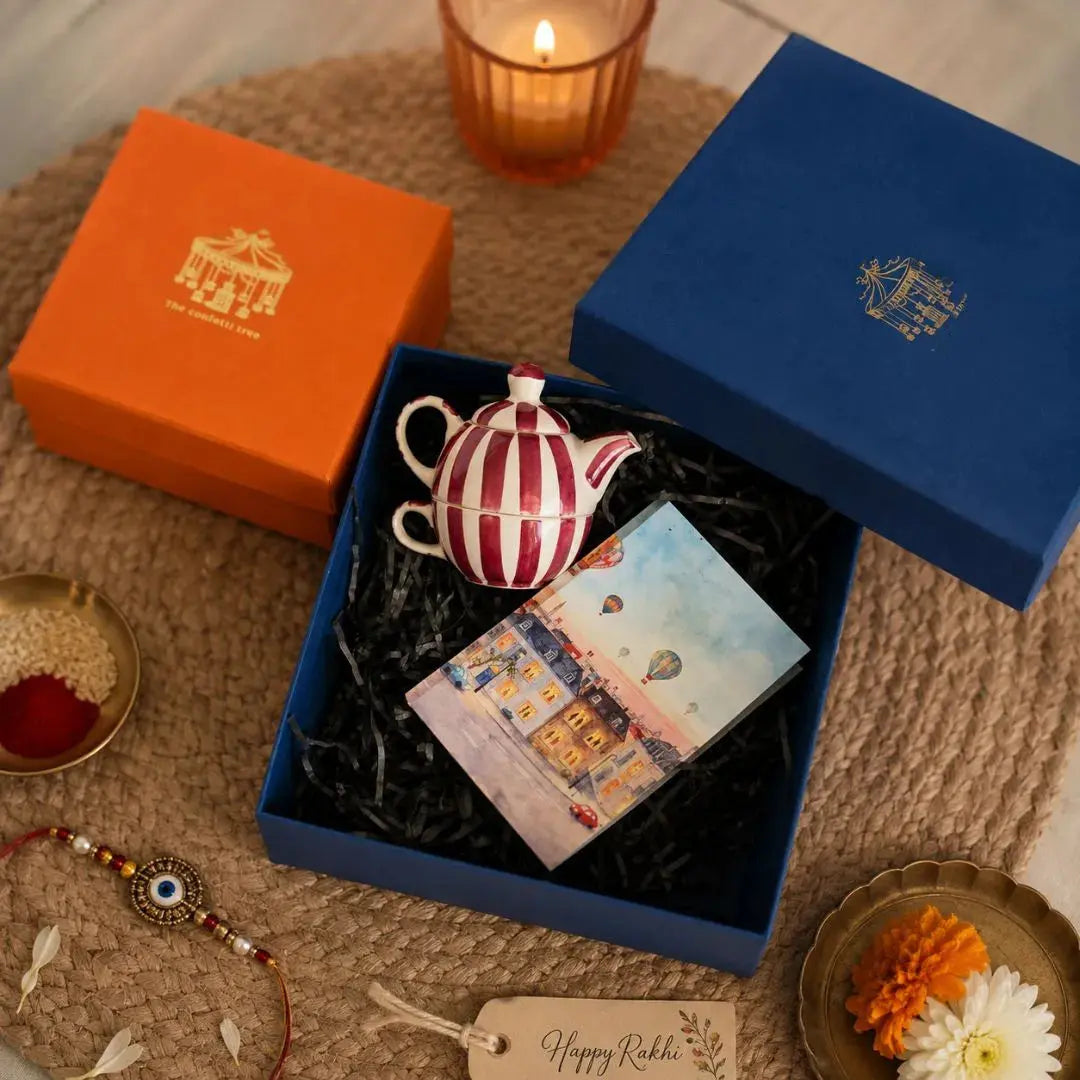 Luxury Rakhi Gift Hamper with Evil Eye Rakhi & Lumba, Handpainted Pink Stoneware Teapot & Cup Set, Hardbound Windows of Wonder Notebook & Greeting Card | Premium Raksha Bandhan Gift Box for Bhai & Bhabhi The confetti tree