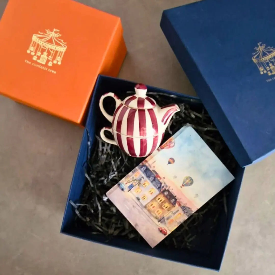 Luxury Rakhi Gift Hamper with Evil Eye Rakhi & Lumba, Handpainted Pink Stoneware Teapot & Cup Set, Hardbound Windows of Wonder Notebook & Greeting Card | Premium Raksha Bandhan Gift Box for Bhai & Bhabhi The confetti tree
