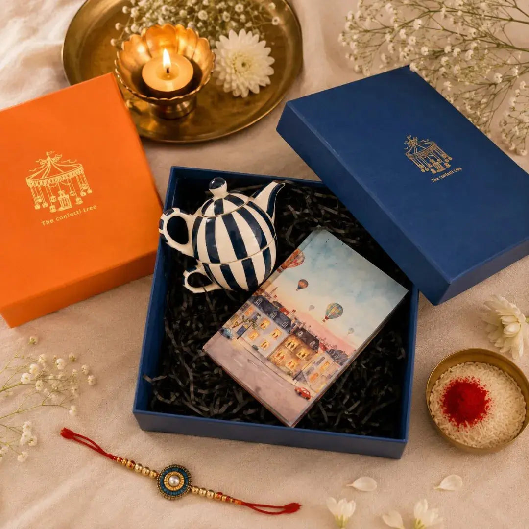 Luxury Rakhi Gift Hamper with Evil Eye Rakhi & Lumba, Handpainted Teal Stoneware Teapot & Cup Set, Hardbound Windows of Wonder Notebook & Greeting Card | Premium Raksha Bandhan Gift Box for Bhai & Bhabhi The confetti tree