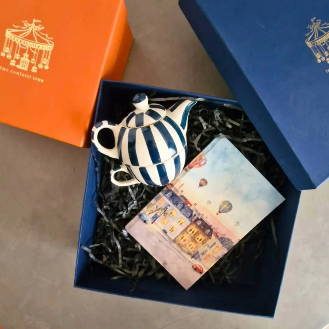 Luxury Rakhi Gift Hamper with Evil Eye Rakhi & Lumba, Handpainted Teal Stoneware Teapot & Cup Set, Hardbound Windows of Wonder Notebook & Greeting Card | Premium Raksha Bandhan Gift Box for Bhai & Bhabhi The confetti tree