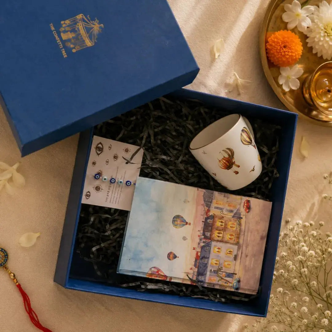 Luxury Rakhi Gift Hamper with Evil Eye Rakhi & Lumba, Hardbound Notebook, Hot Air Balloon Stoneware Coffee Mug & Greeting Card | Premium Raksha Bandhan Gift Box for Bhai & Bhabhi The confetti tree