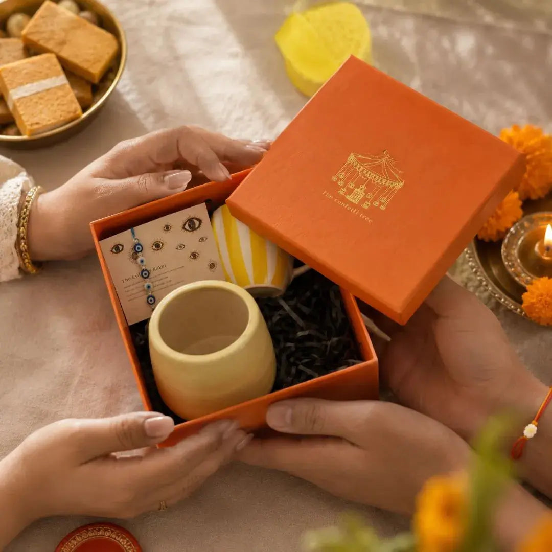Premium Rakhi Gift Hamper with Evil Eye Rakhi & Lumba, Ceramic Planter, Stoneware Coffee Mug & Greeting Card | Luxury Raksha Bandhan Gift Box for Bhai & Bhabhi The confetti tree