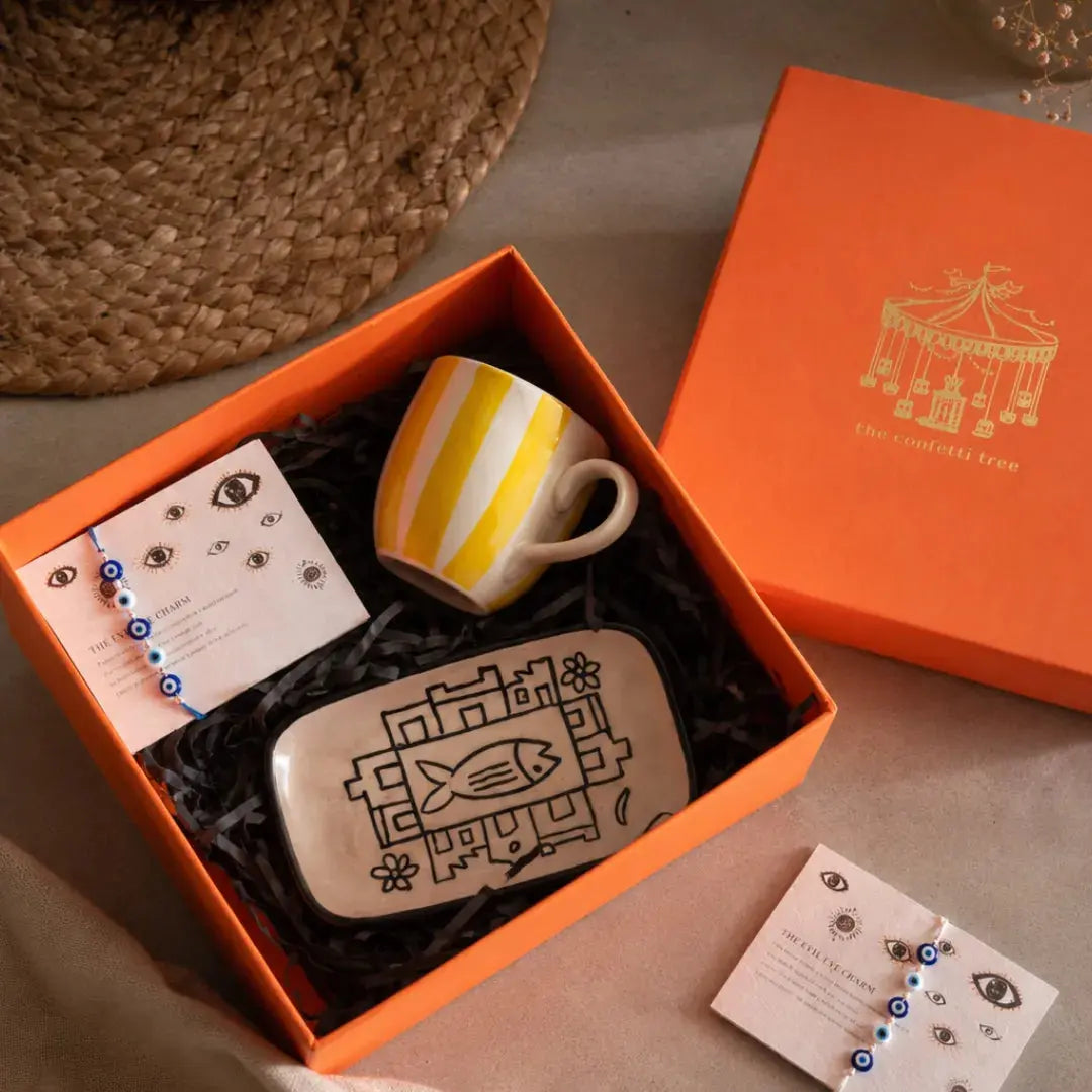 Rakhi Gift Hamper with Evil Eye Rakhi & Lumba Set, Handpainted Yellow Tea Cup & Hand-Illustrated Trinket Tray | Premium Raksha Bandhan Gift Box for Bhai & Bhabhi The Confetti Tree